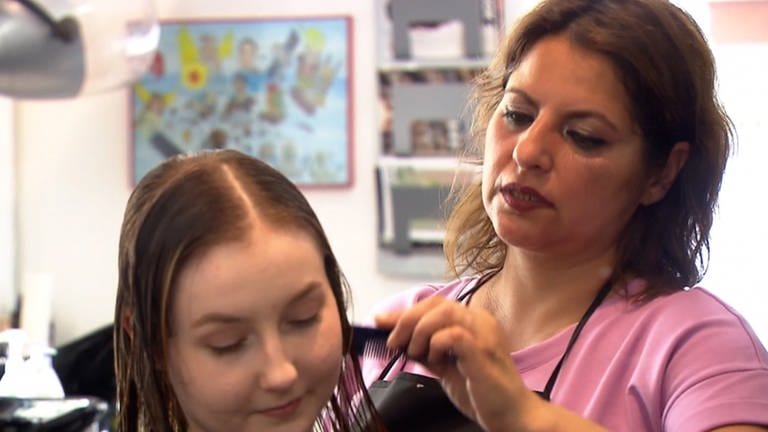 Friseurin Esra schneidet einer Kundin konzentriert die Haare 