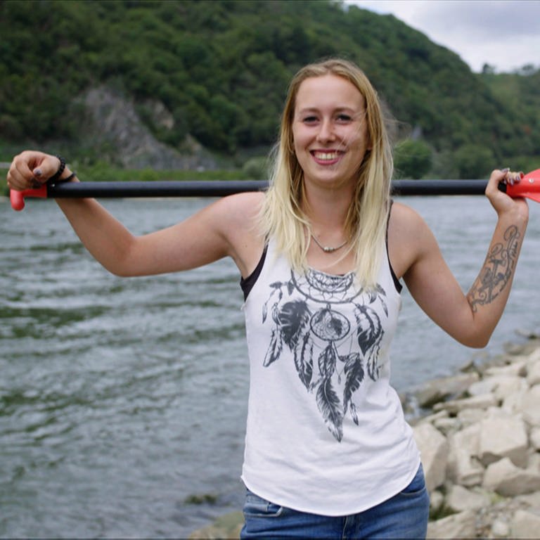 Sportliche, junge Frau steht mit Paddel vor dem Mittelrheintal (Foto: SWR)