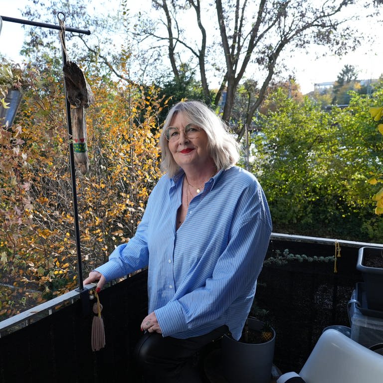 Frau mit grauen Haaren steht auf Balkon