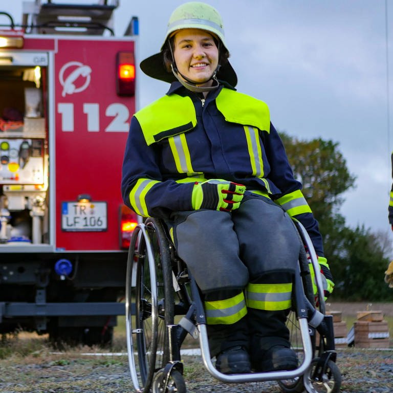 Junge Frau im Rollstuhl vor Feuerwehrauto