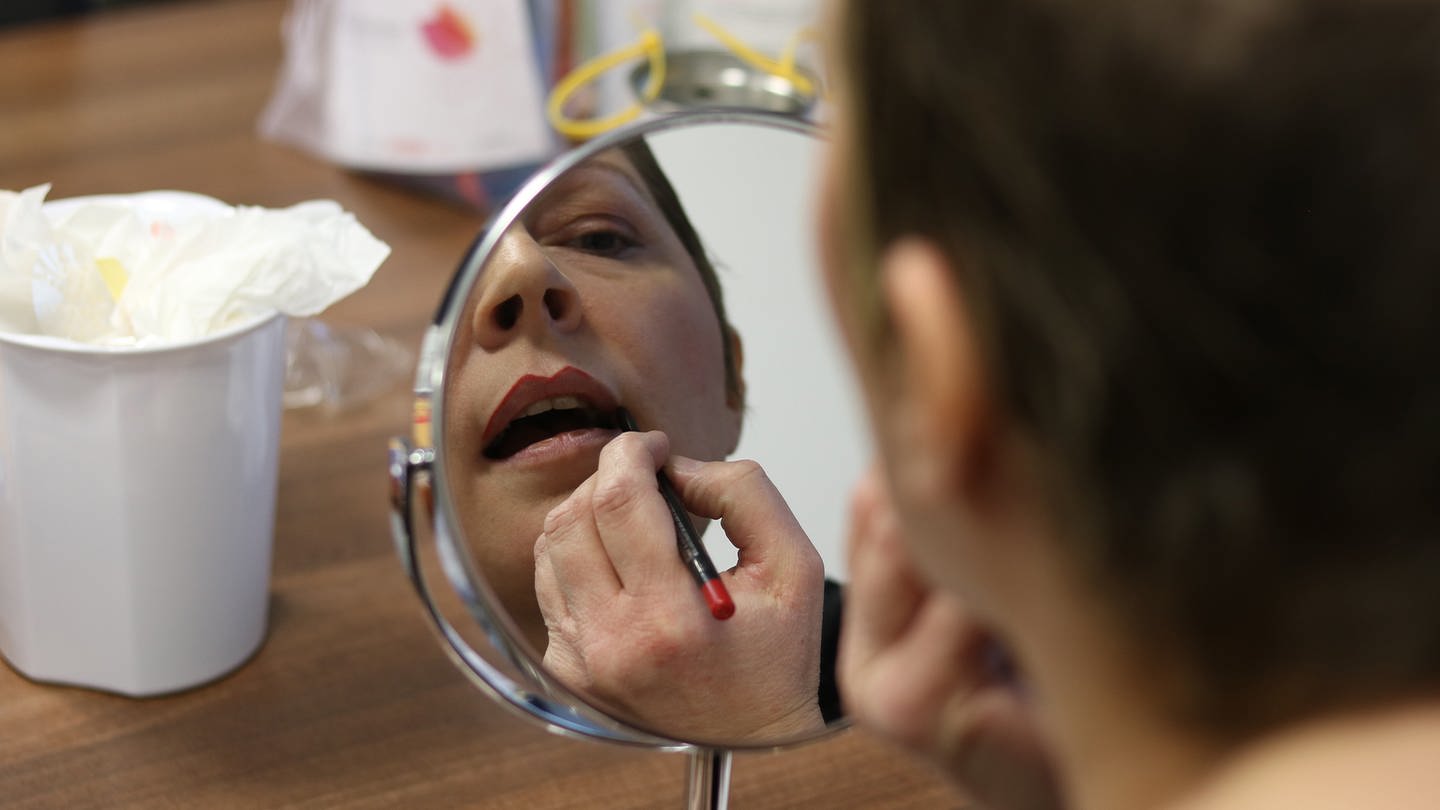 Eine Frau schminkt sich vor dem Spiegel die Lippen. (Foto: SWR)