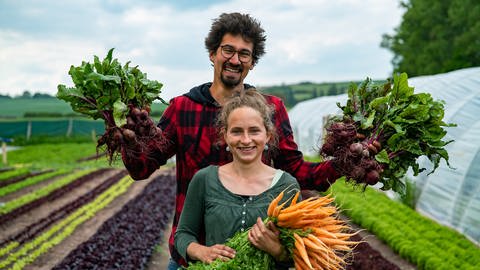 Ein junges heterosexuelles Paar in einem Gemüsegarten mit Gemüse in den Händen (Foto: SWR)