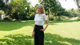 Hannah, Gründerin eines nachhaltigen Modelabels, steht auf einer grünen Wiese.  (Foto: SWR)