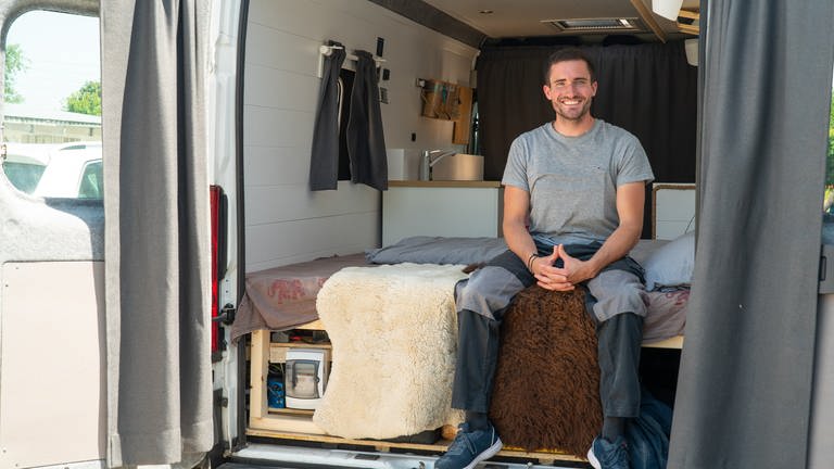 Junger Mann sitzt auf seinem Bett im Camper Van (Foto: SWR)