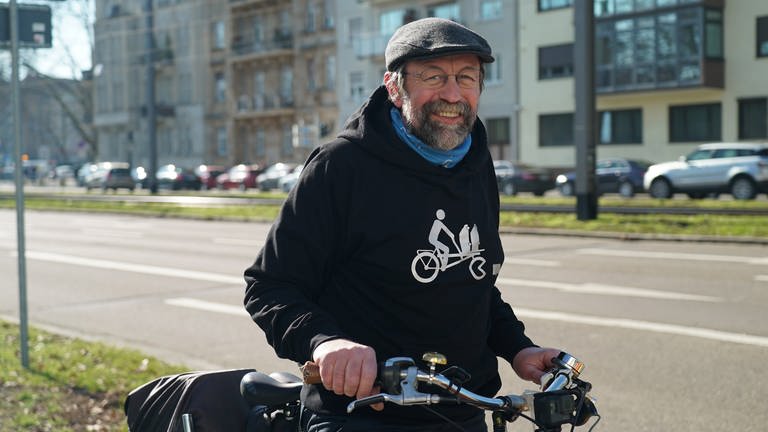 Älterer Herr auf dem Fahrrad. Im Hintergrund das Mannheimer Schloss.