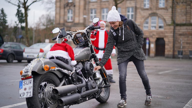 Die Menschen am Straßenrand werfen Geld in eine Spendendose an seiner Harley Davidson. (Foto: SWR)