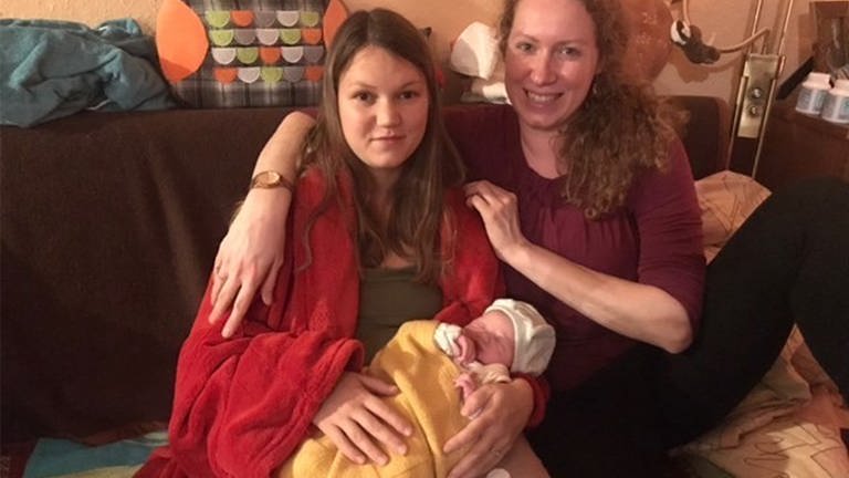 Zwei Frauen sitzen auf dem Sofa, eine hält ein frischgeborenes Baby im Arm.  (Foto: SWR)