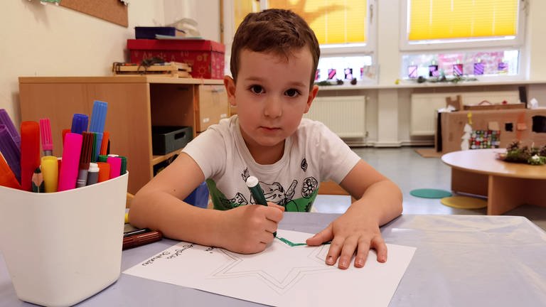 Julian malt im Kindergarten ein Bild mit einem rot-grünen Stern darauf. (Foto: SWR)