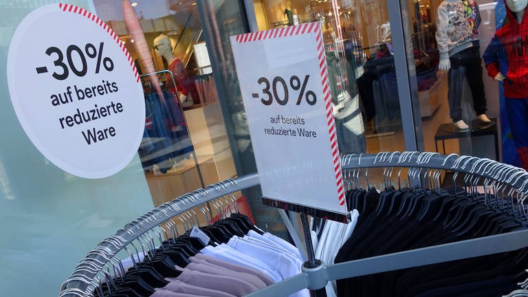 Reduzierter Kleidungsständer mit Schildern, auf denen -30% steht.  (Foto: IMAGO, Ina Peek)