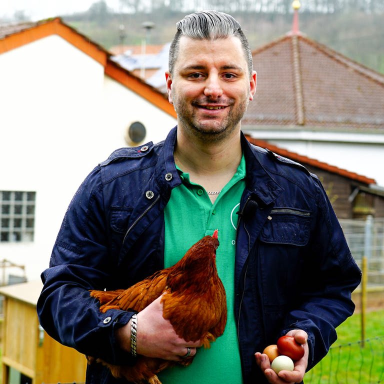 Benjamin, Mann mit braunem Huhn auf dem Arm und drei Eiern in der Hand (Foto: SWR)