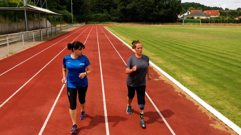 Zwei Frauen joggen auf einem Sportplatz. Die rechte Frau hat eine Beinprothese (Foto: SWR)