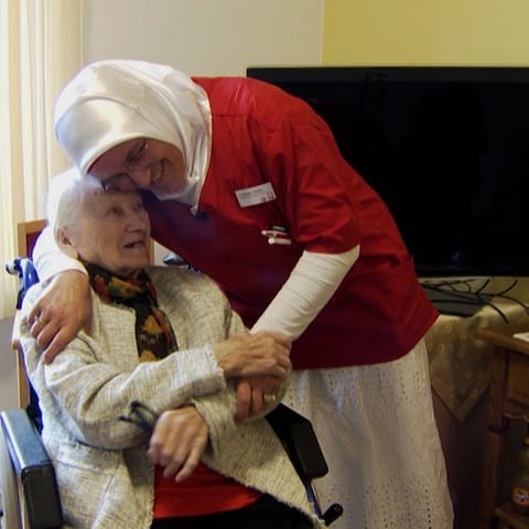 Altenpflegerin lacht zusammen mit Seniorin in Zimmer in Altenheim. (Foto: SWR)