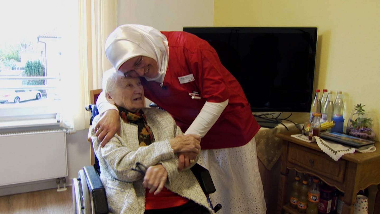 Altenpflegerin lacht zusammen mit Seniorin in Zimmer in Altenheim. (Foto: SWR)