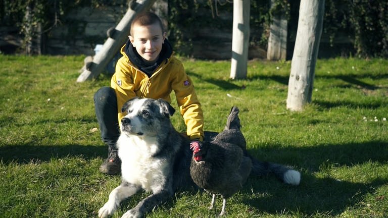 Junge, 9 Jahre alt, auf Wiese mit Huhn Julia (Foto: SWR)