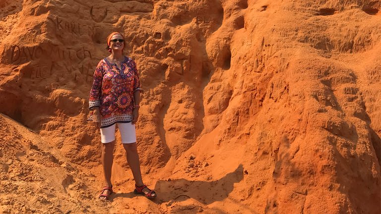 Ältere Dame posiert vor rotem Sandsteinfelsen, Ayers Rock in Australien. (Foto: Ingrid Steegmüller)