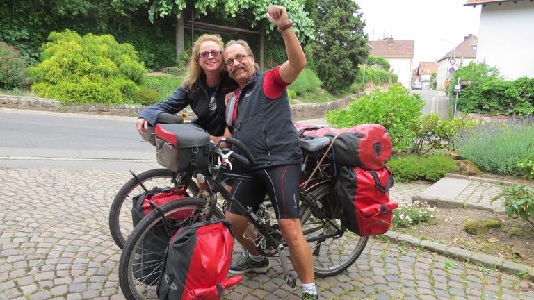 Eine Frau und ein Mann in Fahrradkleidung mit ihren bepackten Fahrrädern. (Foto: SWR)