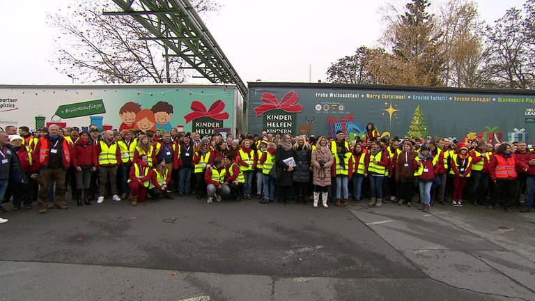Gruppenfoto von den Helfern. Mehrere Dutzend Menschen in roten Jacken und Warnwesten vor zwei LKW mit Aufschrift.  (Foto: SWR)