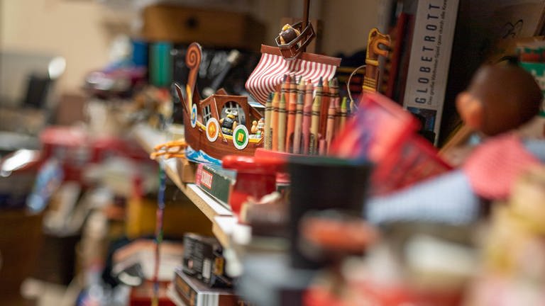 Ein Wikingerschiff und Buntstifte stehen mit anderem Spielzeug in einem Regal. Im „Kaufhaus der Wiederkehr“ in Worms werden Haushaltsgegenstände gebraucht und günstig weiterverkauft. (Foto: SWR)