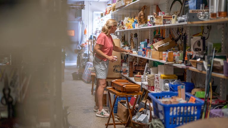 Silke Schulz räumt im „Kaufhaus der Wiederkehr“ in Worms Waren in die Regale. Dort werden Secondhandartikel preiswert verkauft, um einen nachhaltigen Konsum zu ermöglichen und Müll zu reduzieren.