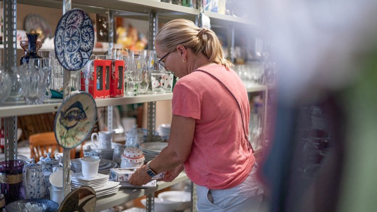 Silke Schulz räumt im „Kaufhaus der Wiederkehr“ in Worms Waren in die Regale. Dort werden Secondhandartikel preiswert verkauft, um einen nachhaltigen Konsum zu ermöglichen und Müll zu reduzieren. (Foto: SWR)