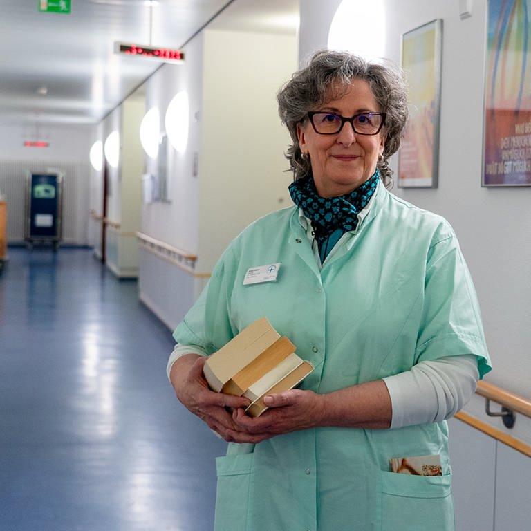 Eine Frau steht in einem Kittel im Flur eines Krankenhauses. Sie ist Grüne Dame im Evangelischen Krankehaus Bad Dürkheim.