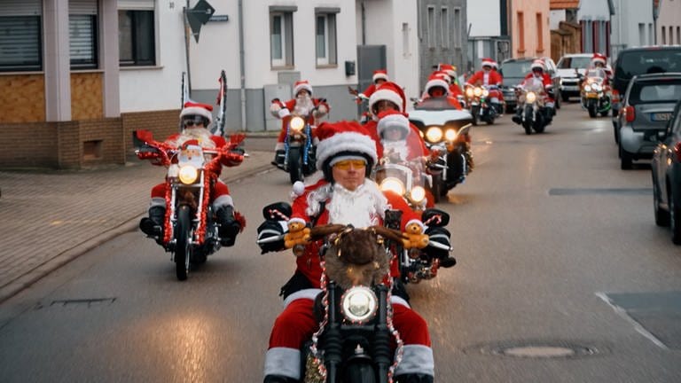 In roten Weihnachtsmänner Kostümen fahren die sogenannten "Riding Santas" auf ihren Motorrädern eine Straße entlang. (Foto: SWR)