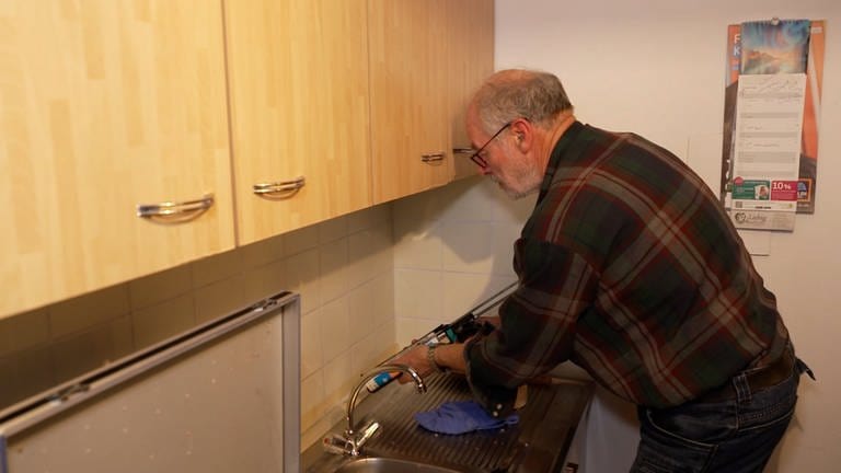 Manfred vom Verein „Alt-Arm-Allein“ repariert eine Fuge an der Küchenzeile. (Foto: SWR)