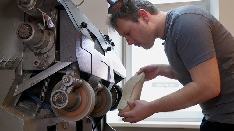 Schuhmacher schleift Schuhsohle passgenau. (Foto: SWR)