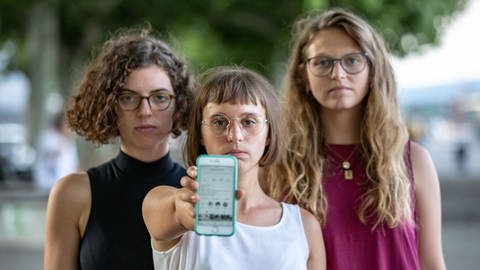 Drei Frauen mit ernster Miene halten Smartphone in die Kamera (Foto: SWR)