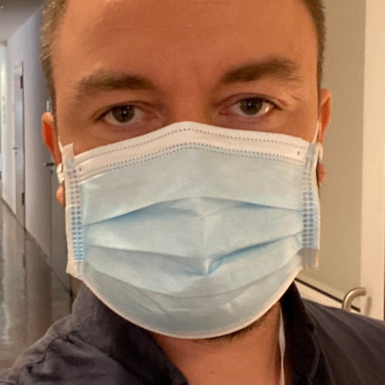 Mann im Krankenhausflur mit einem blauen Mundschutz (Foto: SWR)