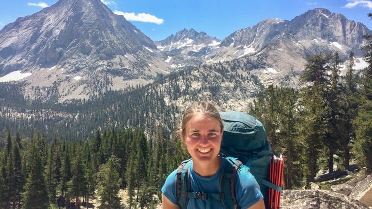 Caroline, 24 Jahre mit Wanderausrüstung vor Gebirge in Amerika