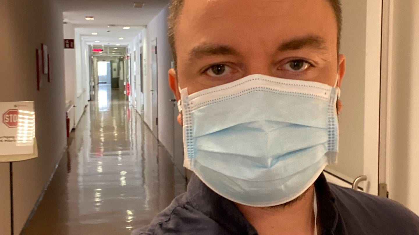 Mann im Krankenhausflur mit einem blauen Mundschutz (Foto: SWR)