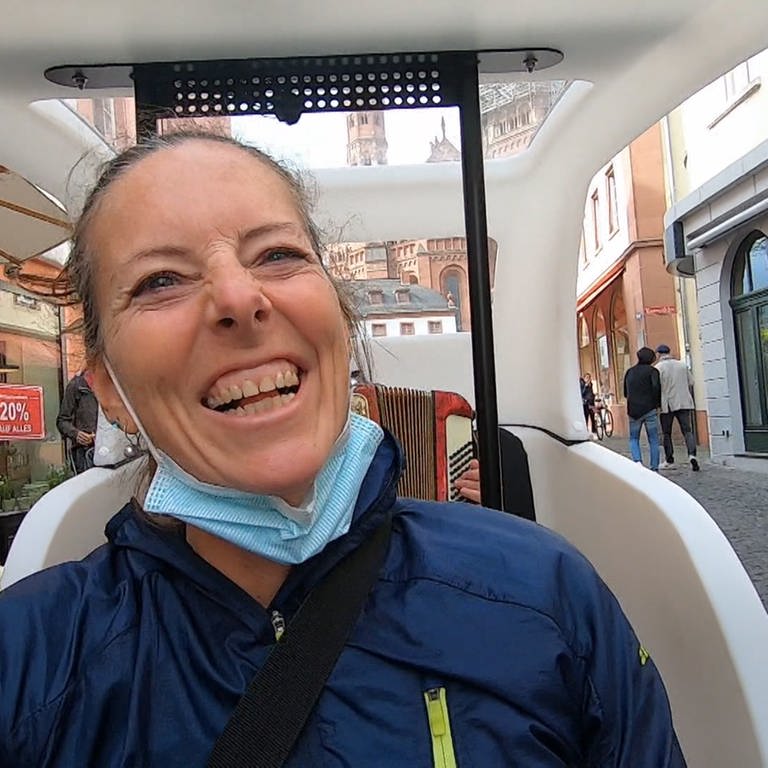 Daiana Neher sitzt in ihrer Fahrrad-Rikscha und lacht während sie durch die Mainzer Altstadt fährt (Foto: SWR)
