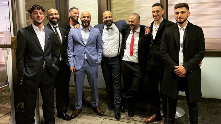 Acht junge Männer im Anzug posieren für ein Foto.