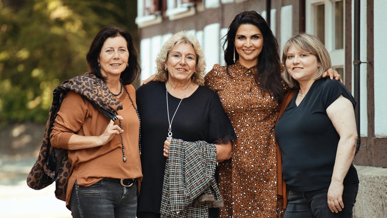 Vier Frauen posieren vor einem Fachwerkhaus. 