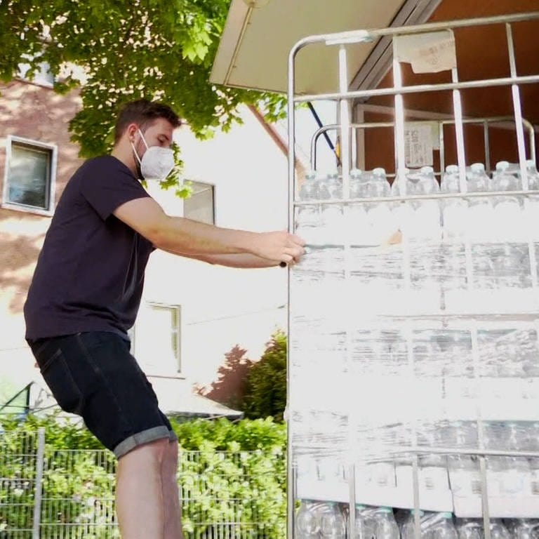 Junger Mann schiebt Rollcontainer mit Wasserflaschen (Foto: SWR)