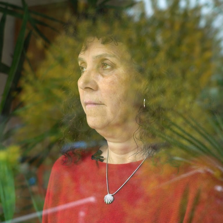 Traurige Frau steht an einem Fenster und blickt in die Ferne