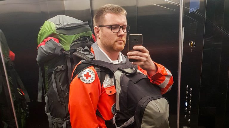 Rouven trägt seine DRK-Ausrüstung und einen großen Rucksack. Vier Wochen war er als Notfallsanitäter in der Ukraine im Einsatz.