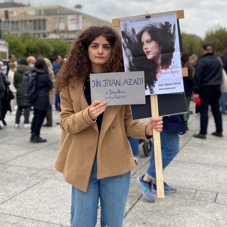 Eine junge Frau hält in Mainz bei einer Demo für Freiheit im Iran zwei Schilder in den Händen. (Foto: SWR, Damaris Diener)
