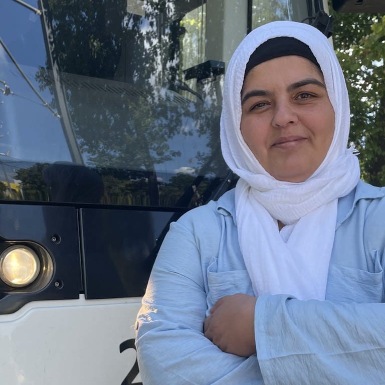 41 Jährige Frau steht mit verschränkten Armen vor einer Straßenbahn