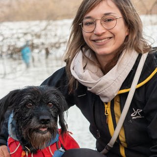 Hund und Frau mit Brille lächeln vor Fluss. (Foto: SWR)