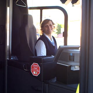 Mona ist Busfahrerin des Jahres. Sie sitzt am Steuer und lächelt in die Kamera. (Foto: SWR)