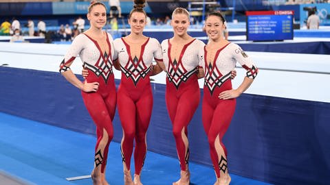 Die vier deutschen Turnerinnen, die sich für Olympia qualifiziert haben, stehen nebeneinander in ihrem weiß-roten Ganzkörperanzug in der Wettkampfstätte in Tokio bei den olympischen Spielen.  (Foto: picture-alliance / Reportdienste, Picture Alliance | Marijan Murat )