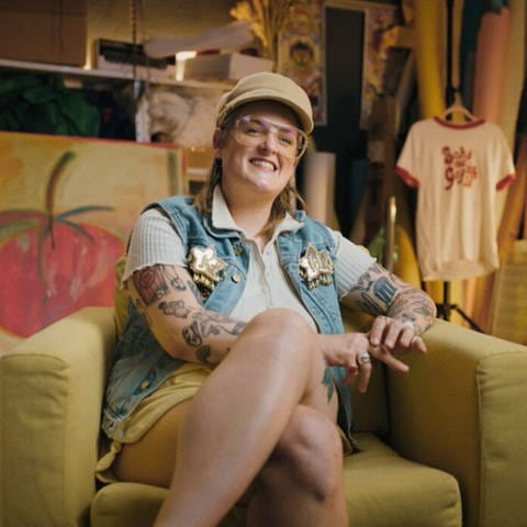 Influencerin Kim Hoss, vom Podcast „The Sirens Collective”, sitzt auf einem Sofa und lächelt in die Kamera. (Foto: SWR)