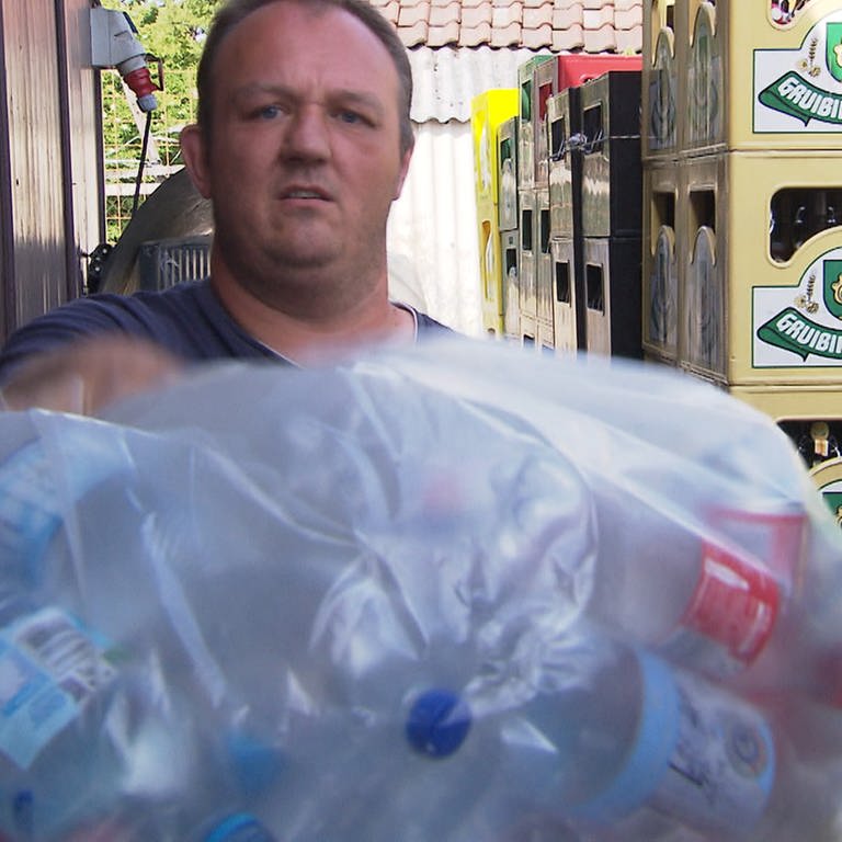 Getränkehändler hält Platikflaschen in die Kamera