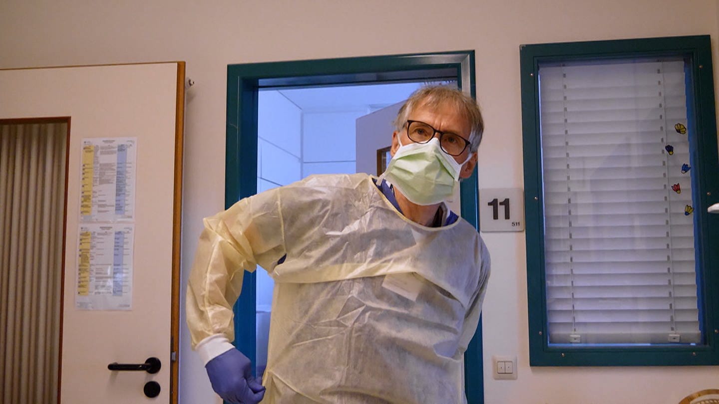 Krankenpfleger Christoph mit Maske und Schutzkleidung