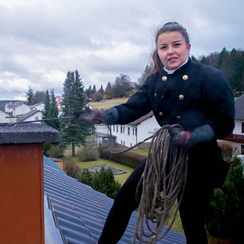 Schornsteinfegerin Janina steht auf einem Dach und reinigt den Schornstein. (Foto: SWR)