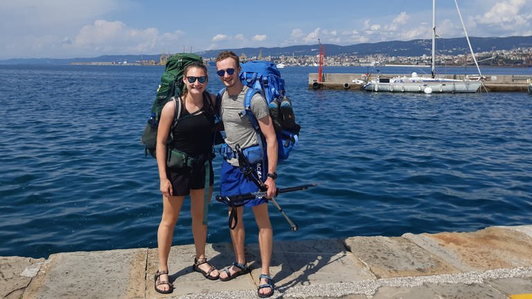 Zwanzigjähriger Frau und Mann stehen in Muggia vor dem Meer. 