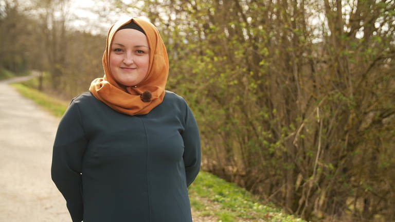 Eine junge Muslima mit orangefarbenem Kopftuch auf einem Spazierweg  (Foto: SWR)
