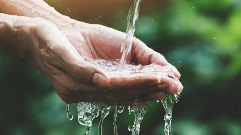 Wasser fließt in eine Hand - Symbolbild zum ARD-Thema #unserWasser: Den Persönlichen Wasserfußabdruck kennen und den Wasserverbrauch pro Person senken, das ist Klimaschutz. (Foto: iStock / Mintr)